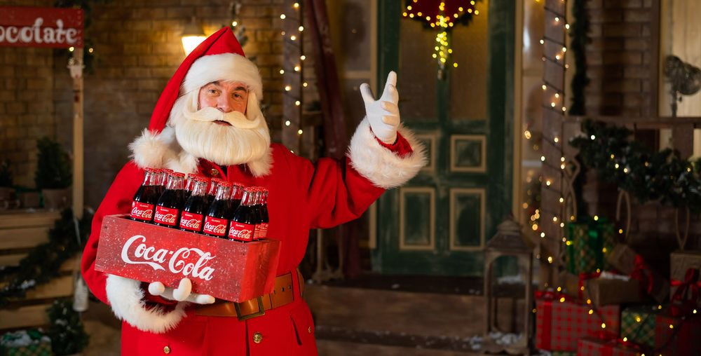 portrait of santa claus holding a package of coca cola bottles. christmas greeting card