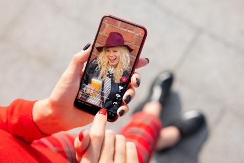 Femme moderne consulte mode sur réseaux sociaux via smartphone.