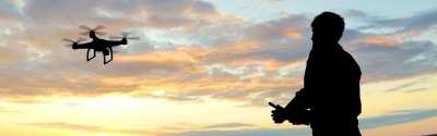 Pilote de drone avec concentration, ciel peint de couleurs au coucher du soleil.